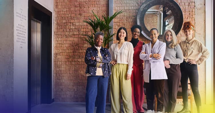 Six women stand confidently together in a modern office, symbolizing empowerment and leadership