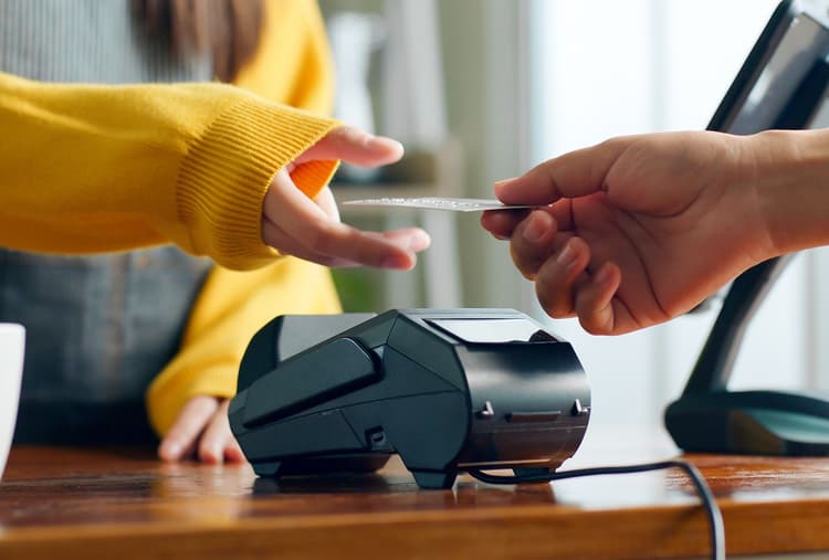 Person handing a credit card to a cashier to pay. 